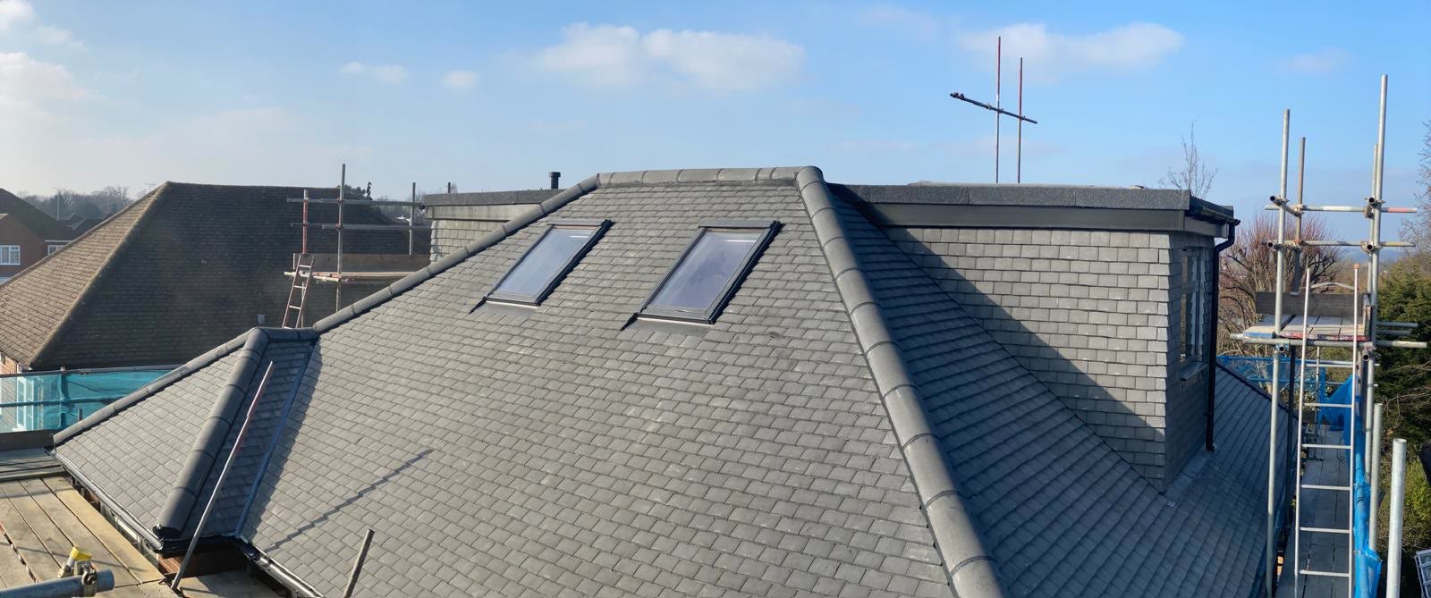 Wide view of a new hipped pin tile roof with two roof windows and ridge tiles